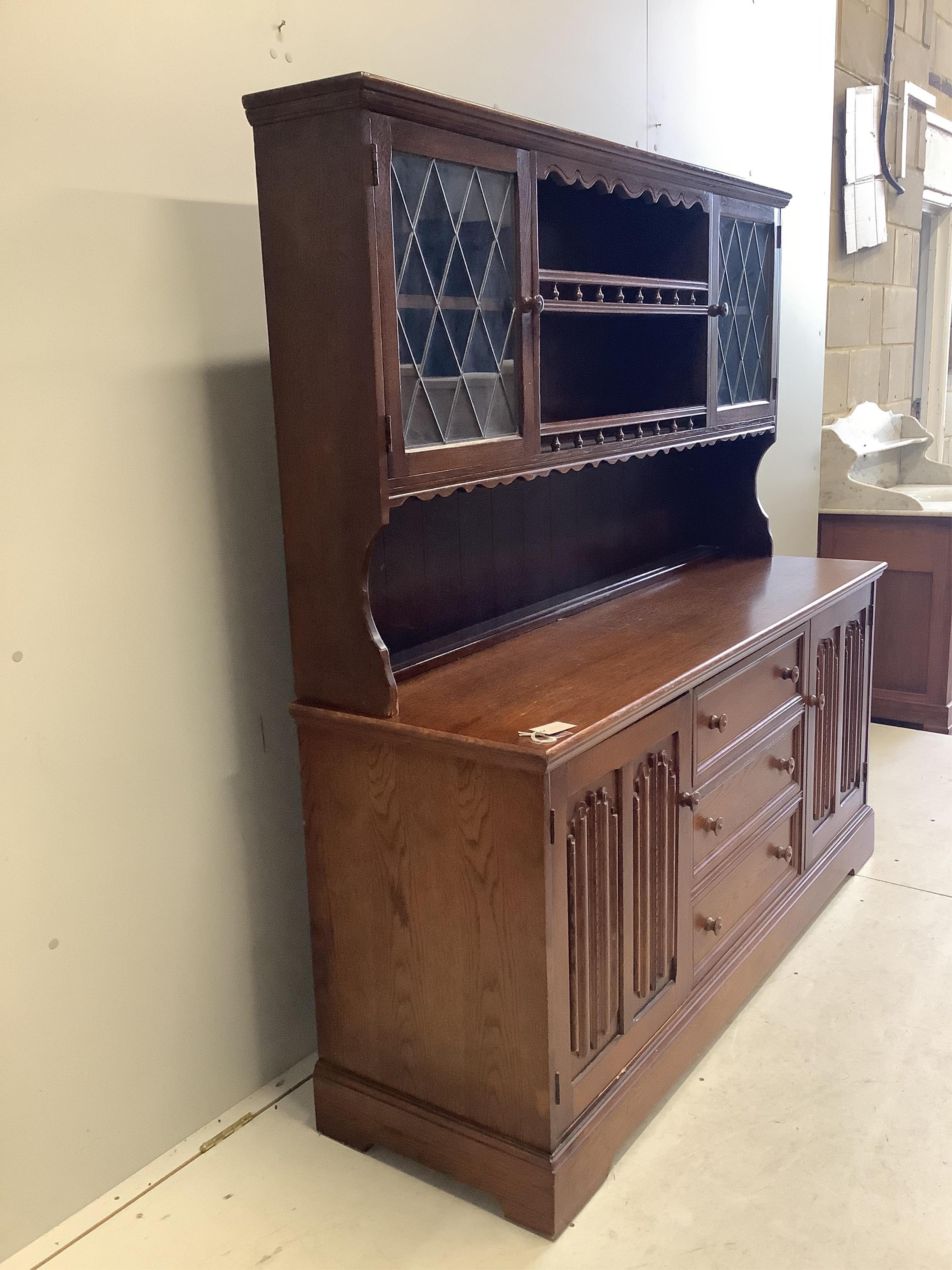 A reproduction oak dresser, the cupboards with linen fold carved fronts, width 160cm, 48cm, height 164cm. Condition - fair to good